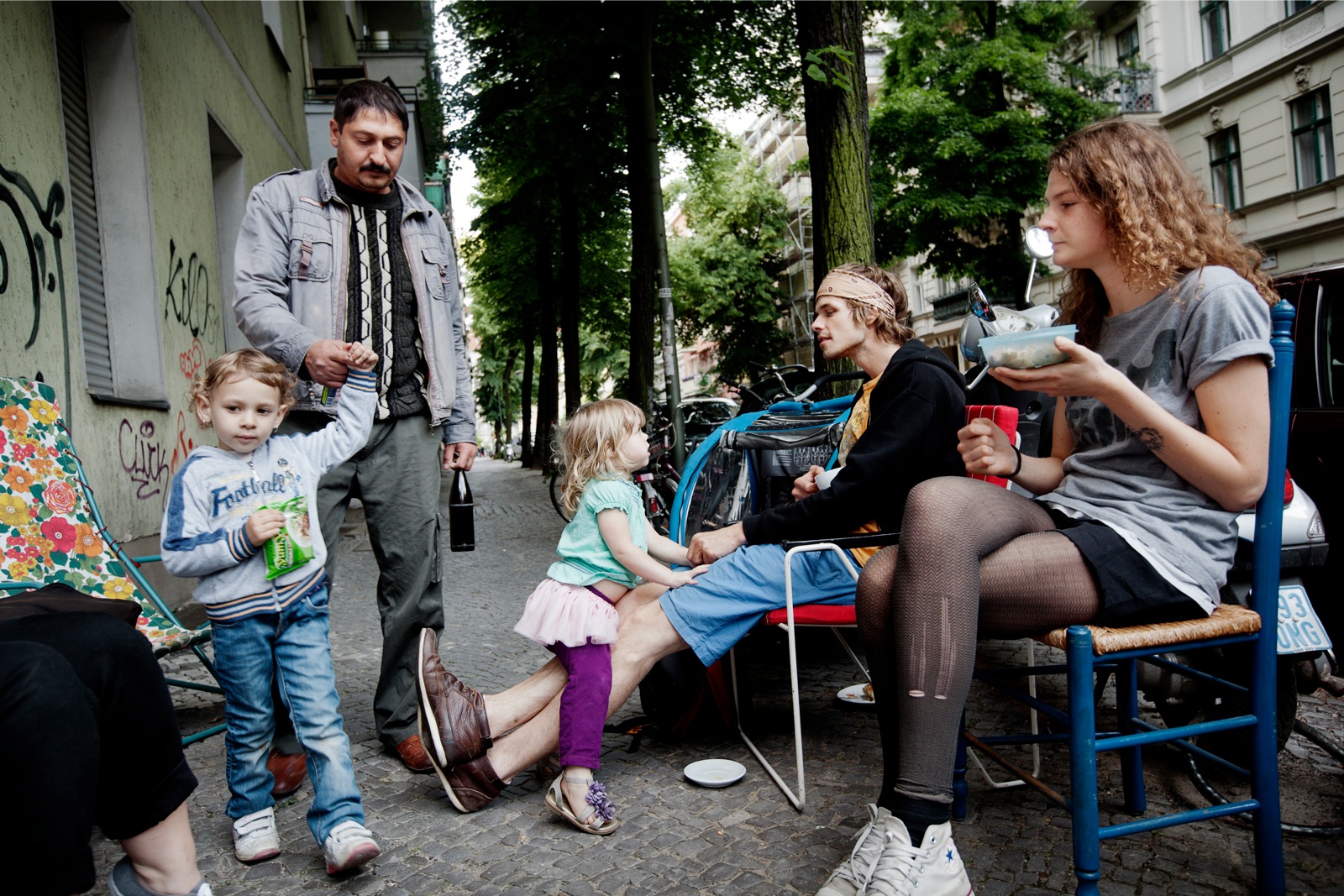 Een bewoner van de snel veranderende achterstandswijk Neukölln in Berlijn passeert een café met jonge Amerikanen en Canadezen op het terras. Foto: Daniel Rosenthal