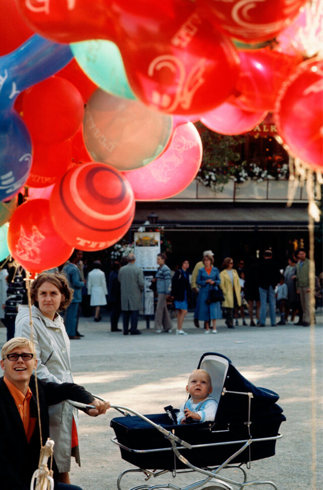 Een baby in een kinderwagen kijkt naar een tros ballonnen